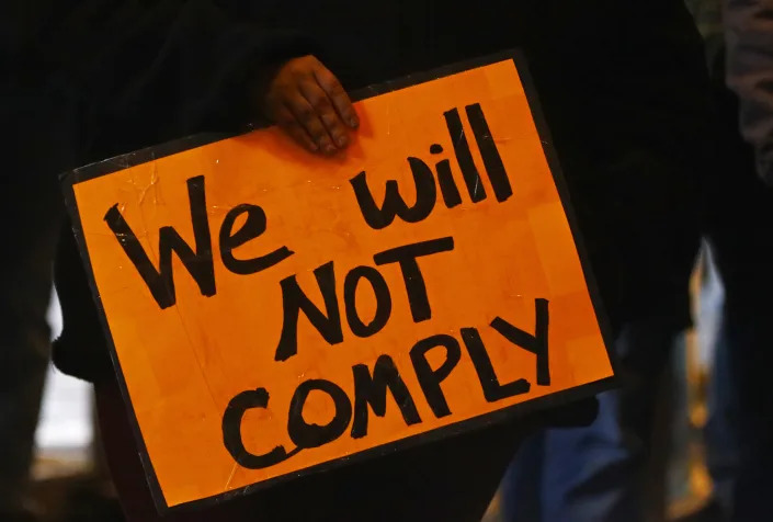 An anti-vax protester holds a sign