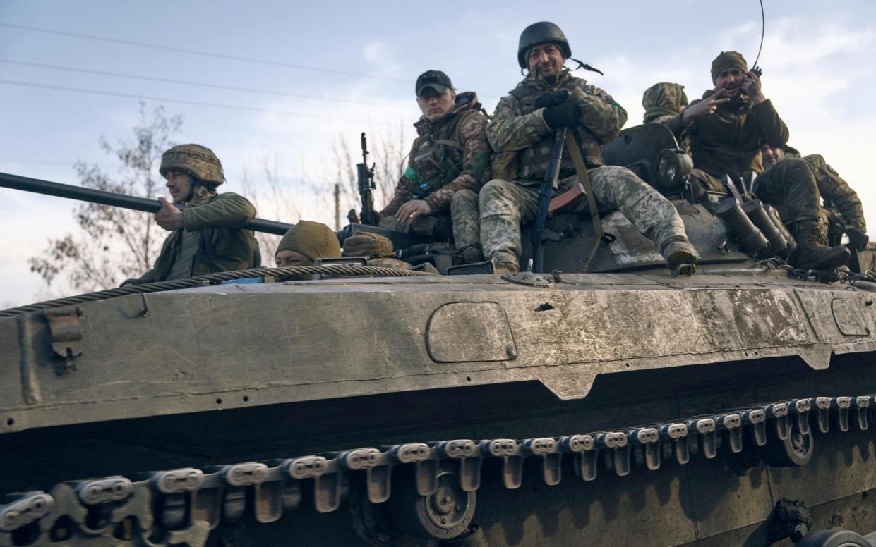 Ukrainian soldiers ride atop an APC on the frontline in Bakhmut - LIBKOS/AP