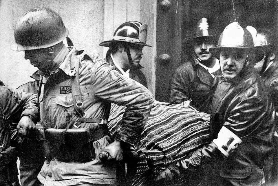 Soldiers and firefighters carry a body wrapped in a poncho