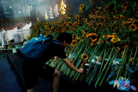 Pro-democracy activist lays sunflowers at a memorial site for anti-extradition bill protester Marco Leung, who died after falling from a scaffolding at the Pacific Place complex while protesting, in Hong Kong