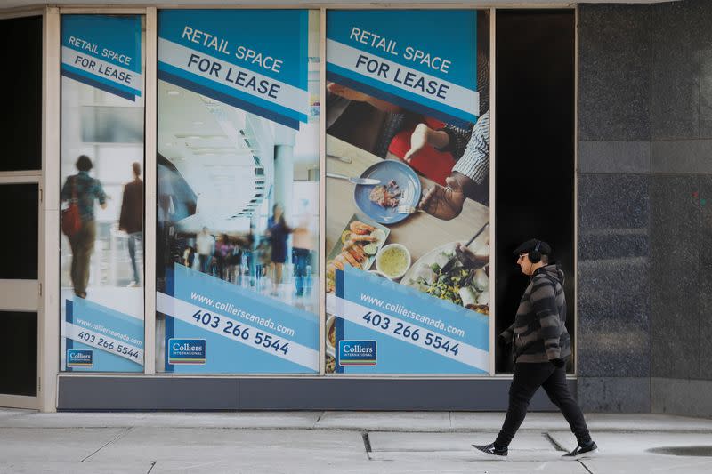 FILE PHOTO: A man walks past a For Lease sign at a downtown office building in Calgary