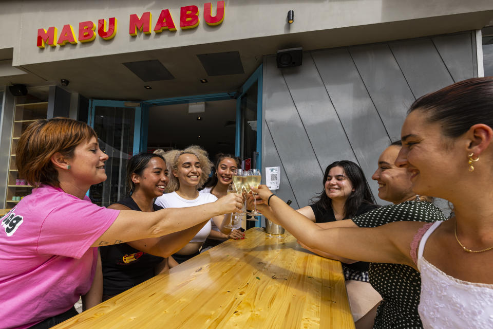 Maskless patrons celebrate with a drink outside Big Esso at Federation Square in Melbourne, Friday, after emerging from Covid lockdown. Source: AAP