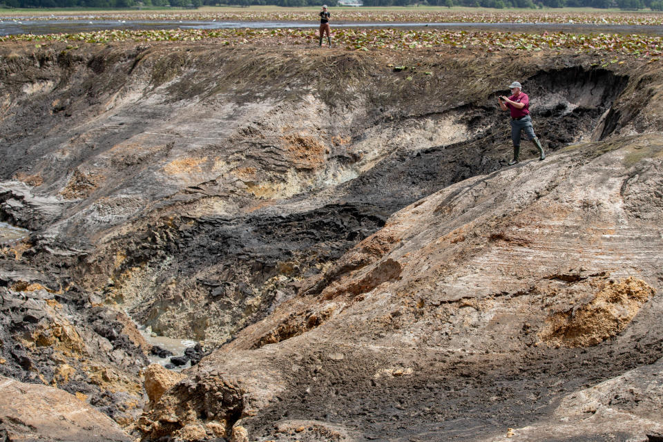 Retired Florida Fish and Wildlife Conservation Commission Biologist Michael Hill takes photos from the edge of Porter Sink in a dried-up Lake Jackson Monday, June 7, 2021.