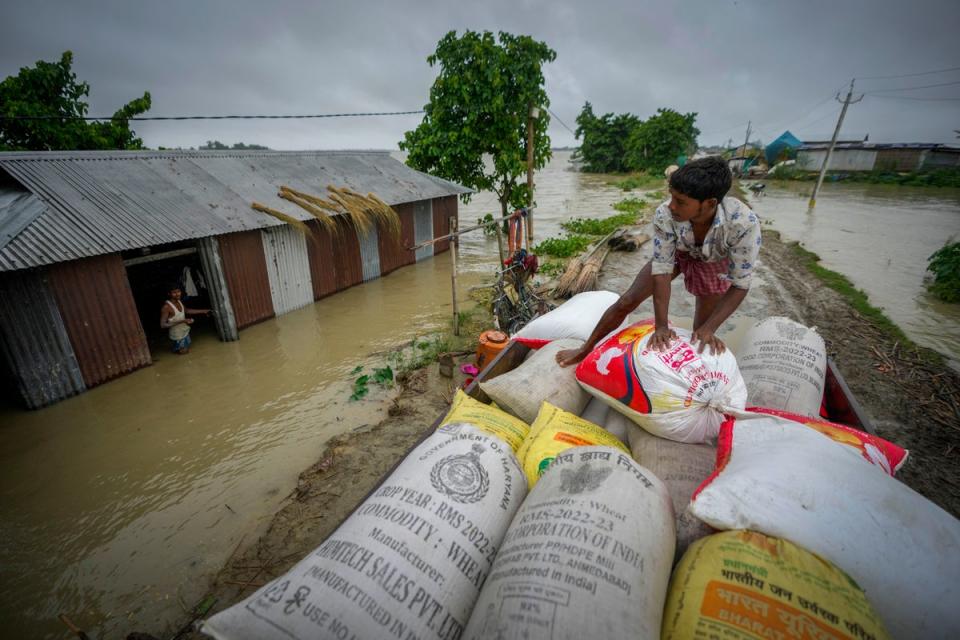 A flood affected person loads sacks of rice on a vehicle to transport to a safer place from his submerged house in Sildubi village in Morigaon, Assam (AP)