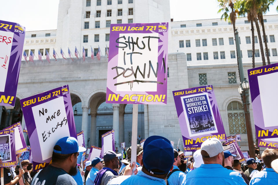 A man holds a picket sign reading “shut it down” as droves of striking workers converged on the steps of Los Angeles City Hall on Tuesday, Aug. 8, 2023. (Michael Mitsanas / NBC News)