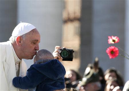 Pope Francis kisses a child as he arrives to lead the general audience in Saint Peter's Square at the Vatican March 5, 2014. REUTERS/Alessandro Bianchi