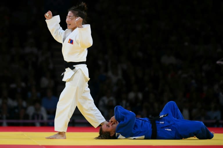 La mongola Baasankhuu Bavuudorj celebra su victoria sobre la española Laura Martínez (azul) durante la semifinal de la categoría -48 kilos de judo en los Juegos Olímpicos de París-2024, en el estadio Campo de Marte de la capital, el 27 de julio de 2024. (Luis ROBAYO)