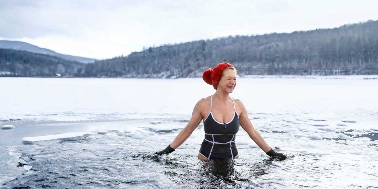 front view of active senior woman in swimsuit outdoors in water in winter, cold therapy concept