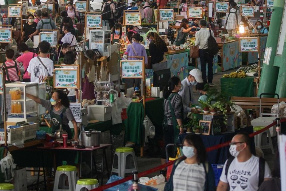 國內二十四日新增五千零九十二個本土病例，新北、桃園及台北等三都病例數破千。民眾下午前往台北花博農民市集，戴口罩落實防疫措施。（中央社）