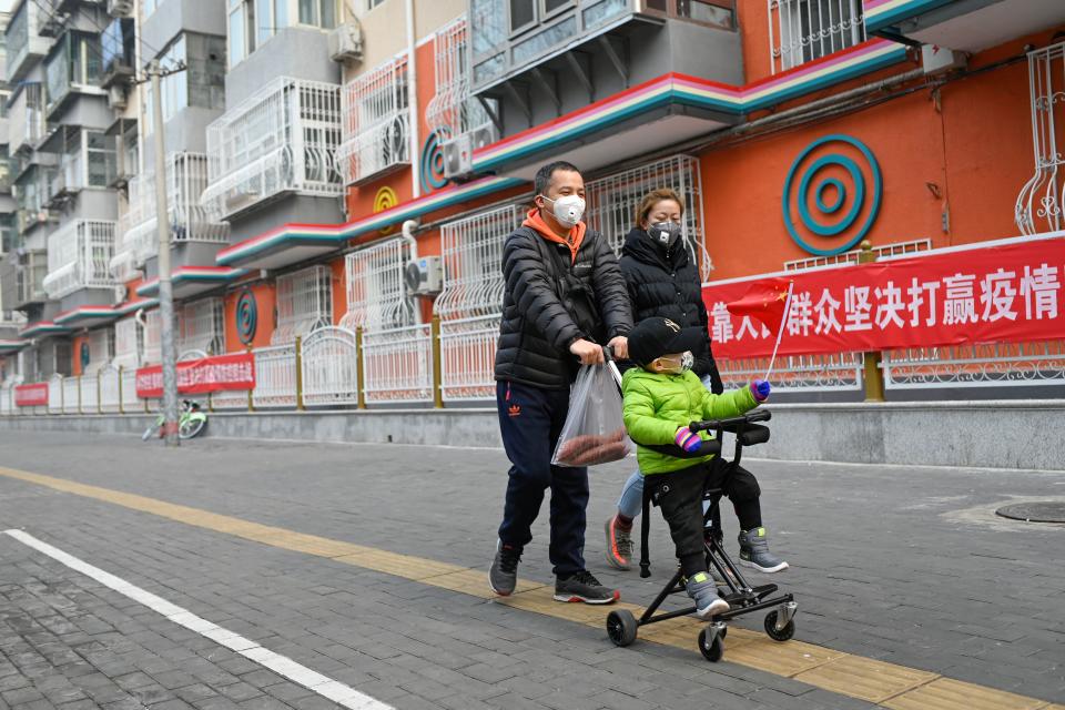 A boy wearing a face mask waves a Chinese national flag as he sits on a stroller in Beijing on February 13, 2020. - The number of deaths and new cases from China's COVID-19 coronavirus outbreak spiked dramatically on February 13 after authorities changed the way they count infections in a move that will likely fuel speculation that the severity of the outbreak has been under-reported. (Photo by STR / AFP) (Photo by STR/AFP via Getty Images)