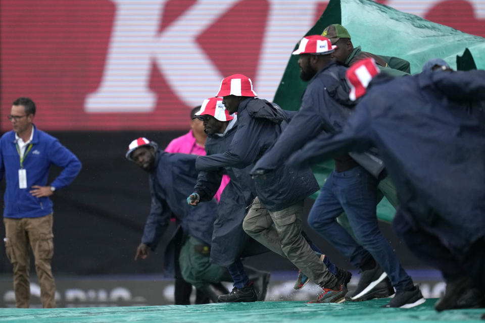 Ground workers remove pull rain cover after rain delayed the start for the first T20 cricket match between South Africa and West Indies, at Centurion Park, South Africa, in Pretoria, South Africa, Saturday, March 25, 2023. (AP Photo/Themba Hadebe)