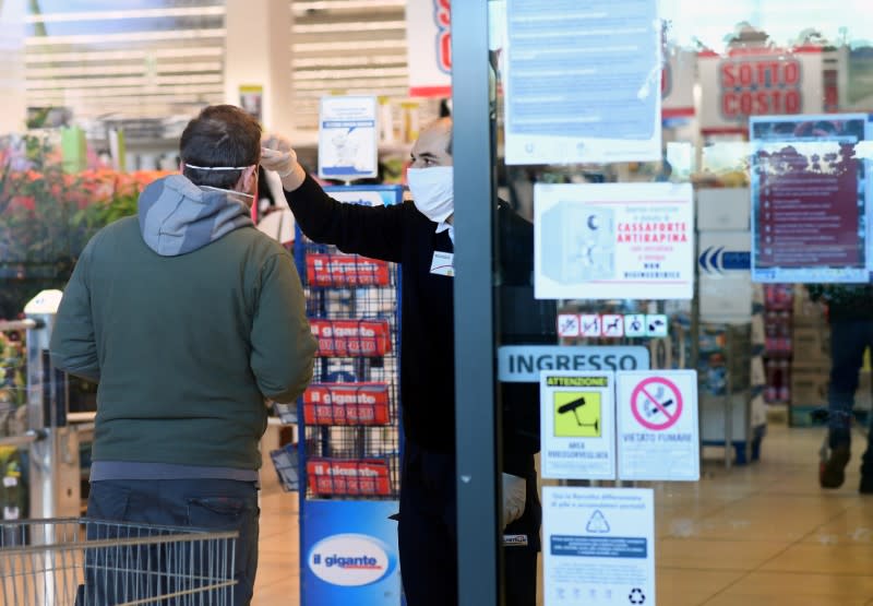 FILE PHOTO: An employee controls the temperature of a man at the entrance of a supermarket, as the spread of the coronavirus disease (COVID-19) continues, in Milan