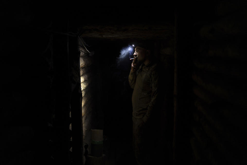 A Ukrainian serviceman from the Azov brigade, known by the call sign Yenot, smokes a cigarette in trenches around one kilometer away from Russian forces on the frontline in Kreminna direction, Donetsk region, Ukraine, Friday, April 12, 2024. (AP Photo/Alex Babenko)