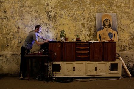 A member of the "Assemblea Cavallerizza 14:45" movement plays music on his computer at the Cavallerizza Reale building, which is occupied by the movement in Turin, Italy, July 16, 2016. REUTERS/Marco Bello