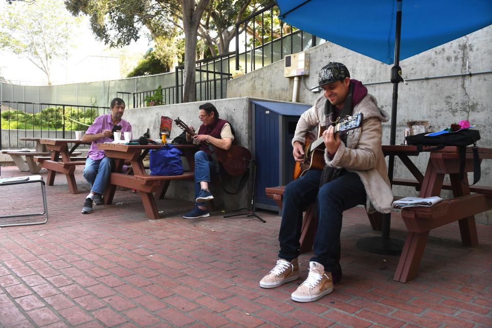 Julian Engel, right, 31, plays guitar as Mark Figurski and Brian Bury chat in the outdoor recreational area of The ARCH, a Ventura shelter run by Mercy House, in May.