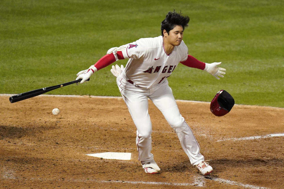 Los Angeles Angels' Shohei Ohtani, right, loses his helmet as swings on a dropped strike three during the sixth inning of a baseball game against the Texas Rangers Monday, April 19, 2021, in Anaheim, Calif. (AP Photo/Mark J. Terrill)