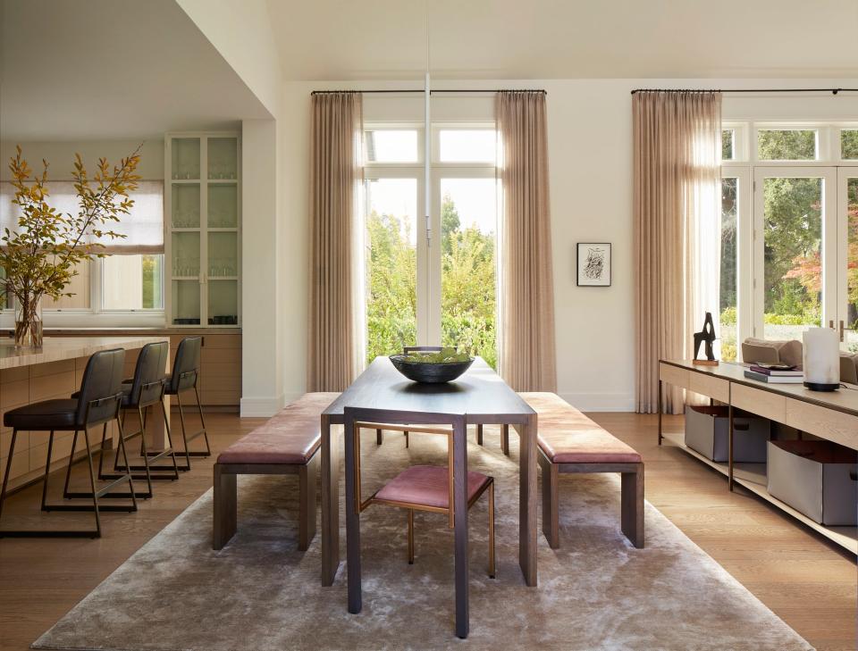 In between the kitchen and living room, a Marmol Radziner custom Glencoe dining table is surrounded by Marmol Radziner Glencoe dining benches and Stephen Kenn Inheritance dining chairs, both upholstered with Spinneybeck Ducale Velour leather.