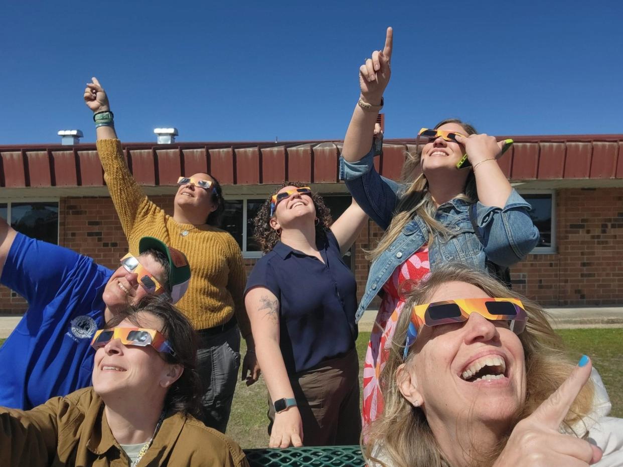 After dismissal on Monday, April 8, 2024, teachers at West Brunswick High School in Shallotte gather outside to check out The Great American Eclipse.