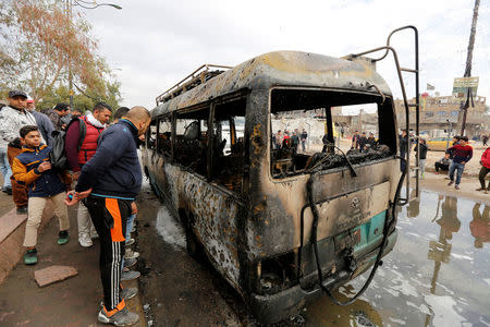 People look at a burned vehicle at the site of car bomb attack in a busy square at Baghdad's sprawling Sadr City district, in Iraq January 2, 2017. REUTERS/Ahmed Saad