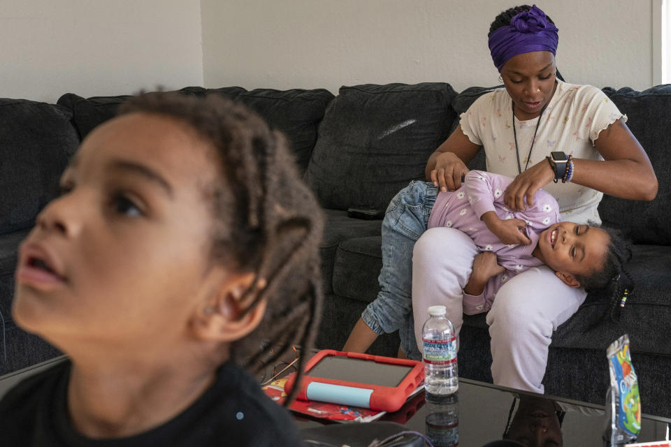 Christina Engram spends time at home with daughter, Neveah, 6, and son, Choncey, left, 4, in Oakland, Calif., on Friday Nov. 24, 2023. Compared with kindergarten, she believed her daughter would be more likely to receive extra attention at the child care center, which has more adult staff per child. “If I put her in public school, I would have to cut my hours, and I basically wouldn’t have a good income for me and my kids,” said Engram, a preschool teacher and a mother of three. (AP Photo/Loren Elliott)