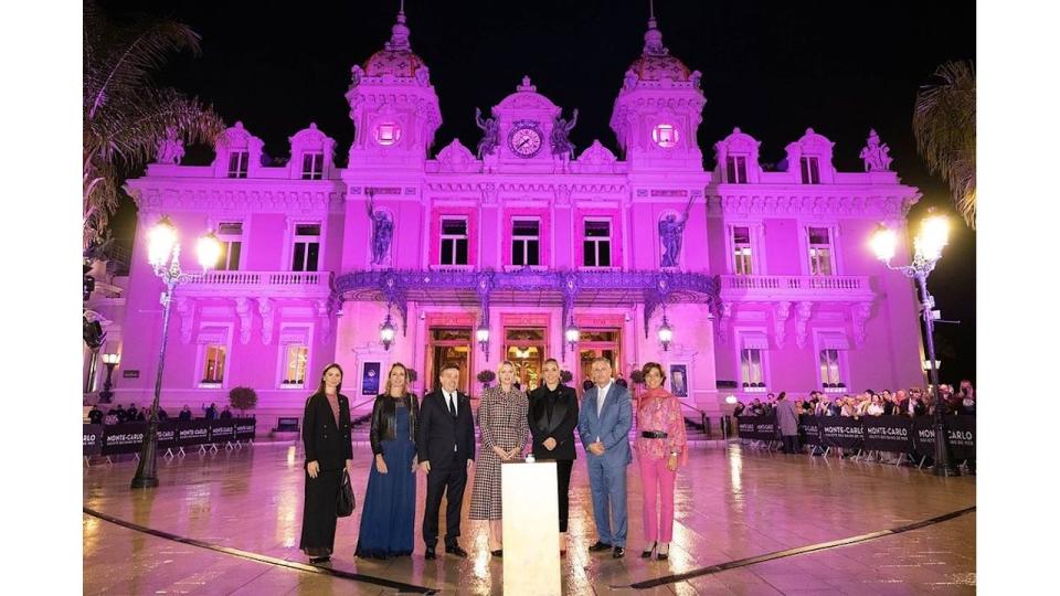 Princess Charlene stands in front of Monaco's Casino Square which is lit up in pink