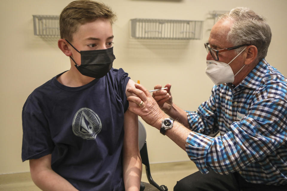 Jack Reed, 13, receives his first dose of the Pfizer-BioNTech vaccine by Dr. David Wahl, who is retired but came to help with the vaccination clinic, Thursday, May 13, 2021 at Vail Health Hospital in Vail, Colo. The Pfizer vaccine was approved for children 12-15-years-old, with Thursday being the first day the kids were able to receive a shot. (Chris Dillmann/Vail Daily via AP)