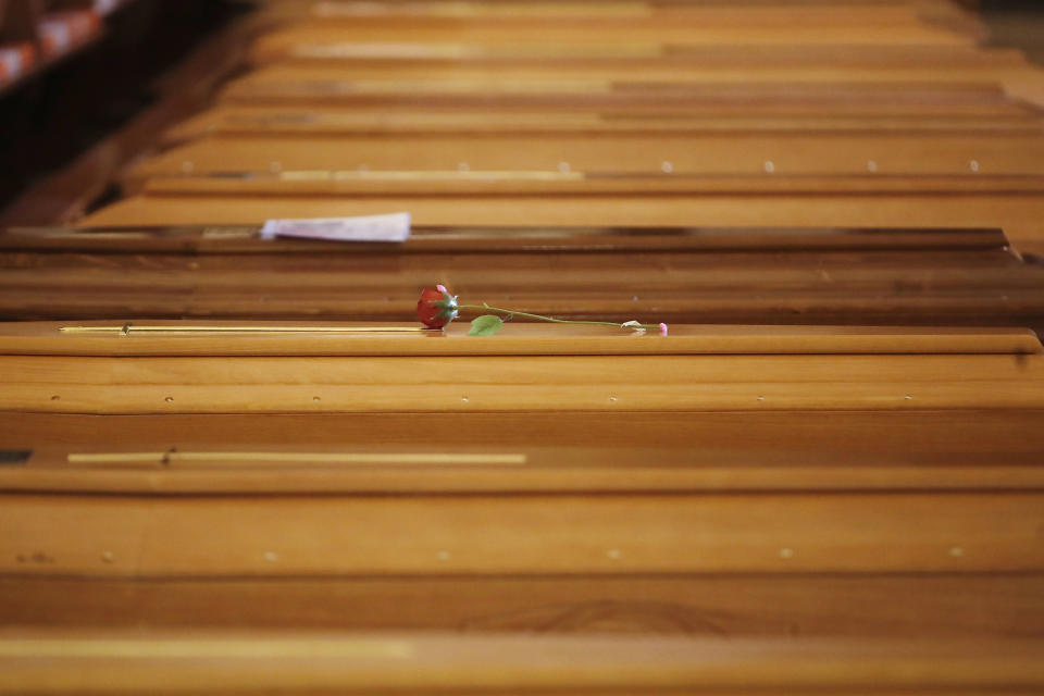 A red rose lies on a coffin lined up along others inside the San Giuseppe church in Seriate, Italy, to be blessed before being sent to crematoriums in Udine and Venice, Northern Italy, Saturday, March 28, 2020. The new coronavirus causes mild or moderate symptoms for most people, but for some, especially older adults and people with existing health problems, it can cause more severe illness or death. (AP Photo/Antonio Calanni)