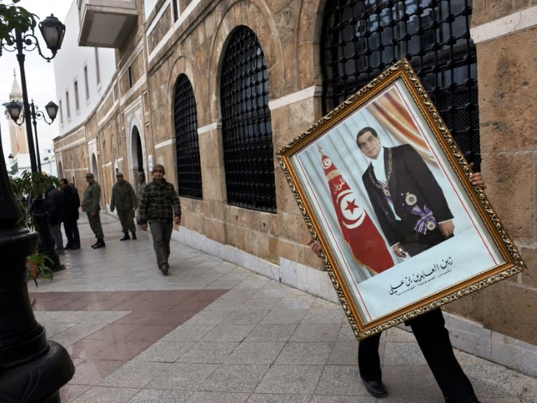 A Tunisian government employee removes a portrait of dictator Zine El Abidine Ben Ali on January 17, 2011 days after his ouster