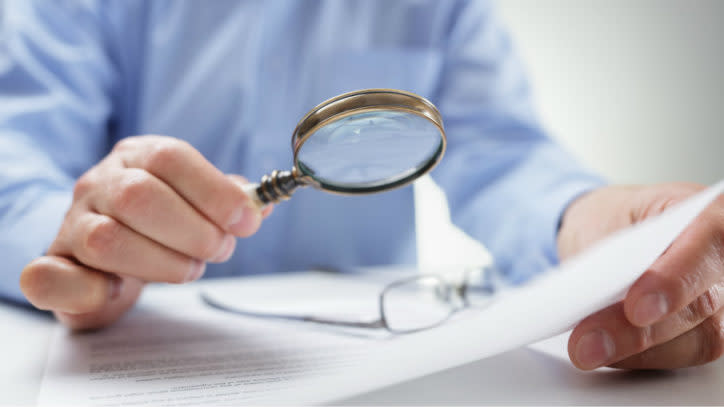 Man holding magnifying glass over a document