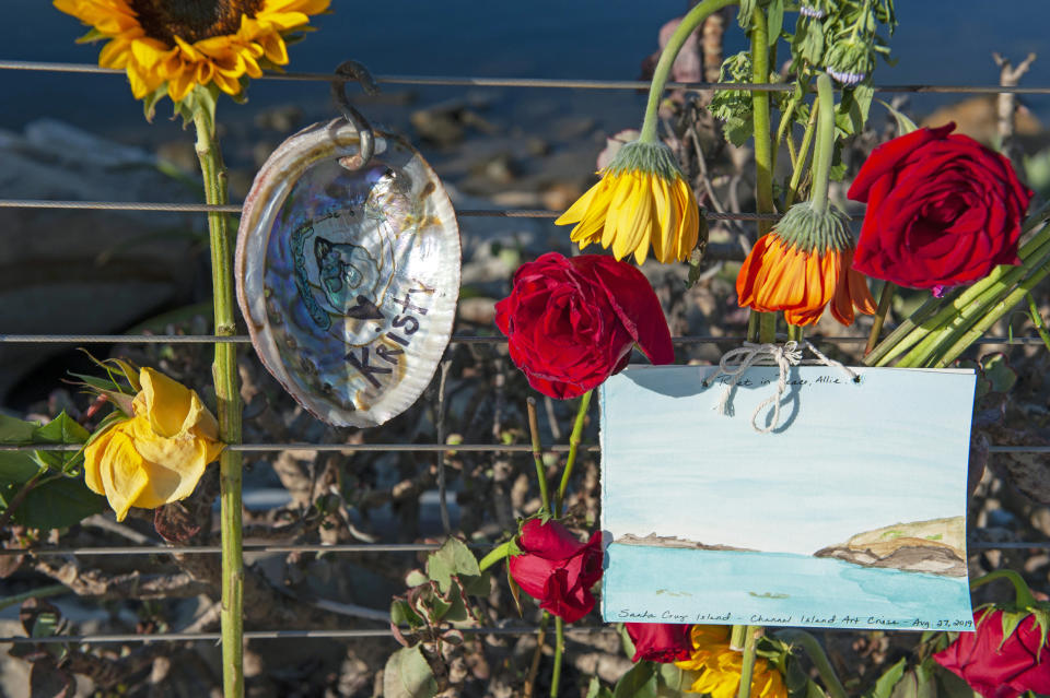 Flowers and handmade art on an abalone shell is displayed at a memorial for the victims of Monday's dive boat fire at the Santa Barbara Harbor on Wednesday, Sept. 4, 2019, in Santa Barbara, Calif. (AP Photo/Christian Monterrosa )