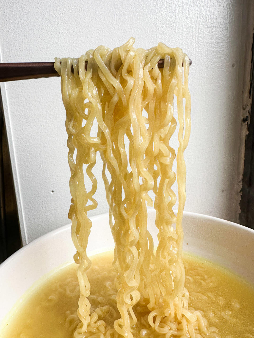 chopsticks holding up maruchan noodles in bowl