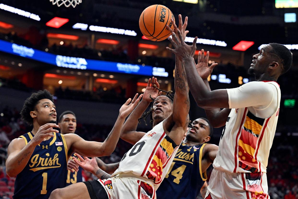 Feb 21, 2024; Louisville, Kentucky, USA; Louisville Cardinals forward Kaleb Glenn (10) and forward Brandon Huntley-Hatfield (5) and Notre Dame Fighting Irish guard Julian Roper II (1) battle for a rebound during the first half at KFC Yum! Center. Mandatory Credit: Jamie Rhodes-USA TODAY Sports