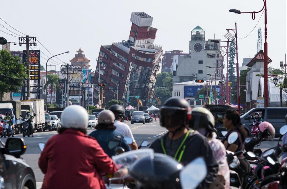 Local residents ride past a damage of building caused by the earthquake in Hualien following the April 3 quake (AFP via Getty Images)