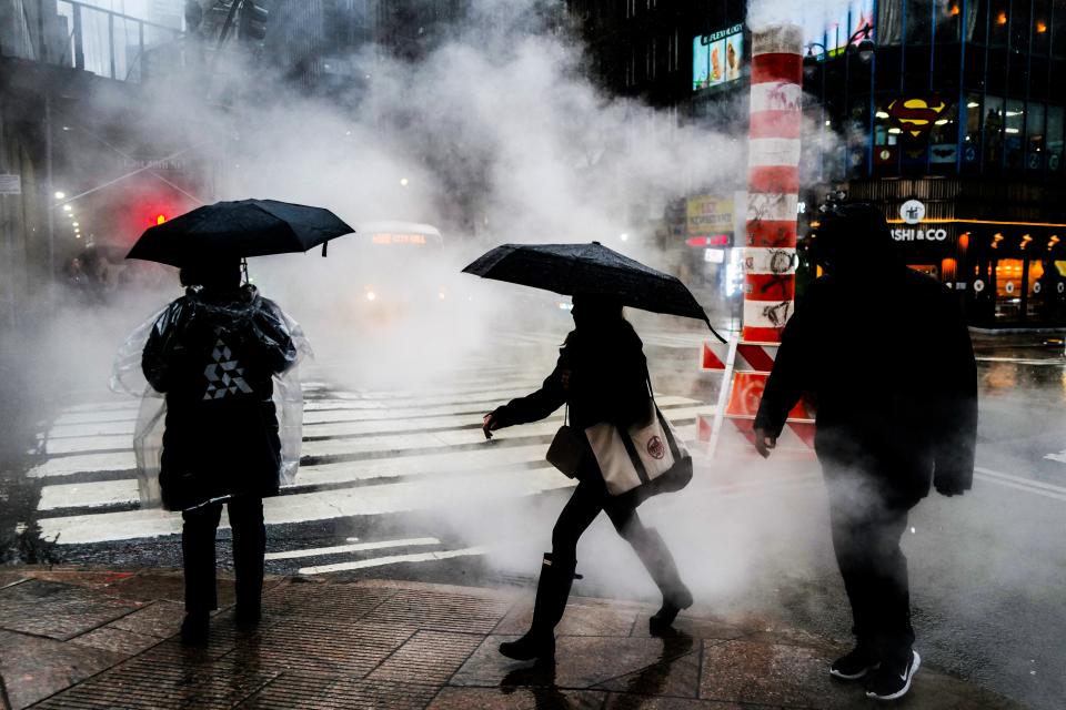 People walk in the street during heavy rain in the Manhattan borough of New York on March 23 (AFP via Getty Images)