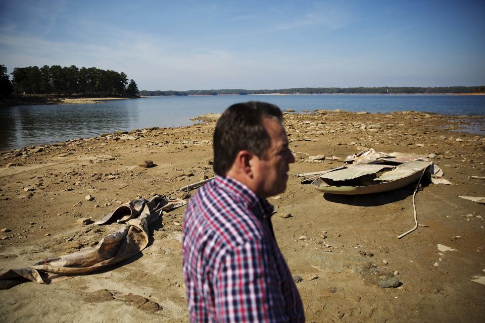 FILE - A sunken boat is exposed by receding water levels on Lake Lanier as U.S. Army Corps of Engineers Natural Resources Manager Nick Baggett looks on in Flowery Branch, Ga., Oct. 26, 2016. A new study finds that climate change is making droughts faster and more furious — and especially one fast-moving kind of drought that can take farmers by surprise. (AP Photo/David Goldman, File)