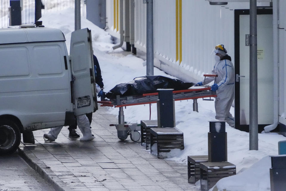 Medical workers load a body into a vehicle outside a COVID-19 hospital in Kommunarka, near Moscow, Russia, Thursday, Jan. 27, 2022. Russia's state coronavirus task force has reported more than 11.3 million confirmed cases and over 328 thousands deaths, by far the largest death toll in Europe. (AP Photo/Pavel Golovkin)