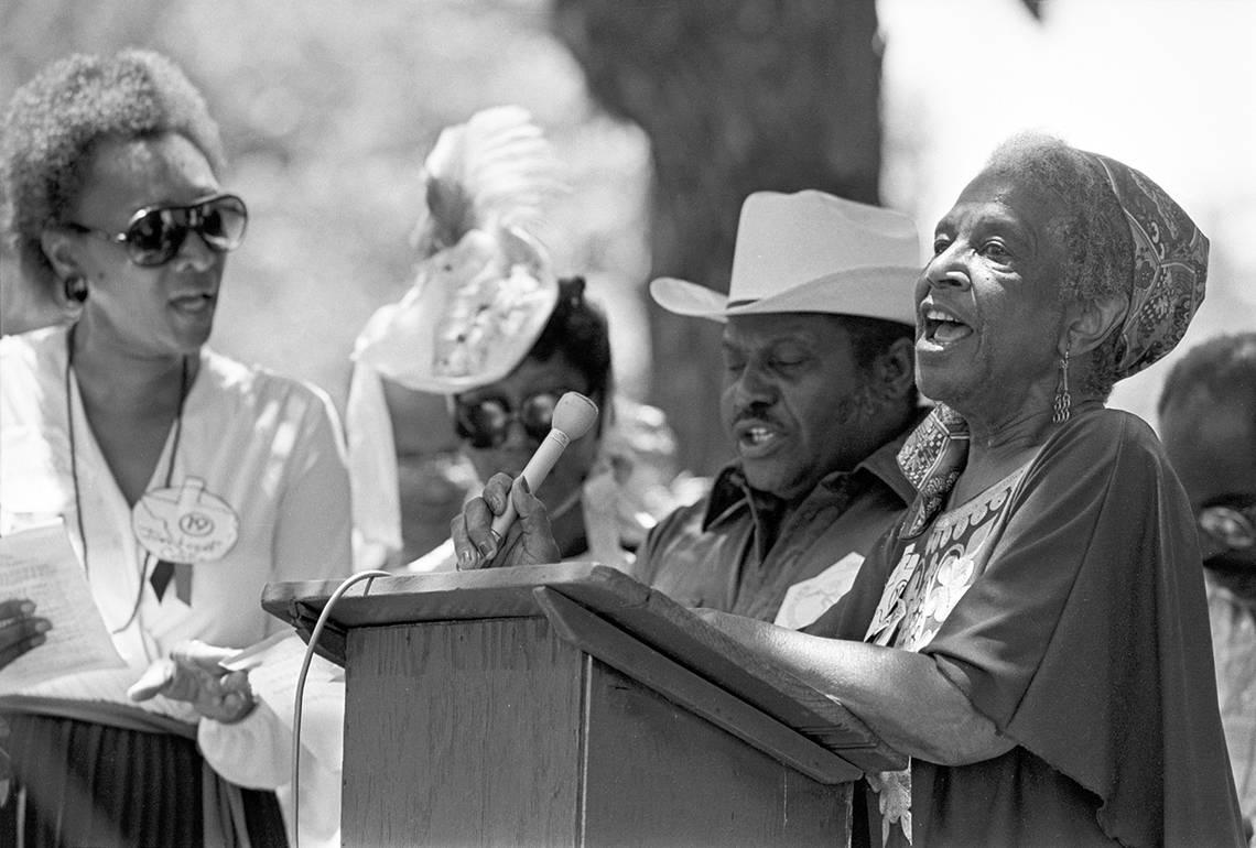 Lenora Rolla, founder of the Tarrant County Black Historical and Genealogical Society, speaks at a podium during 1984’s Juneteenth festivities at Sycamore Park in Fort Worth.