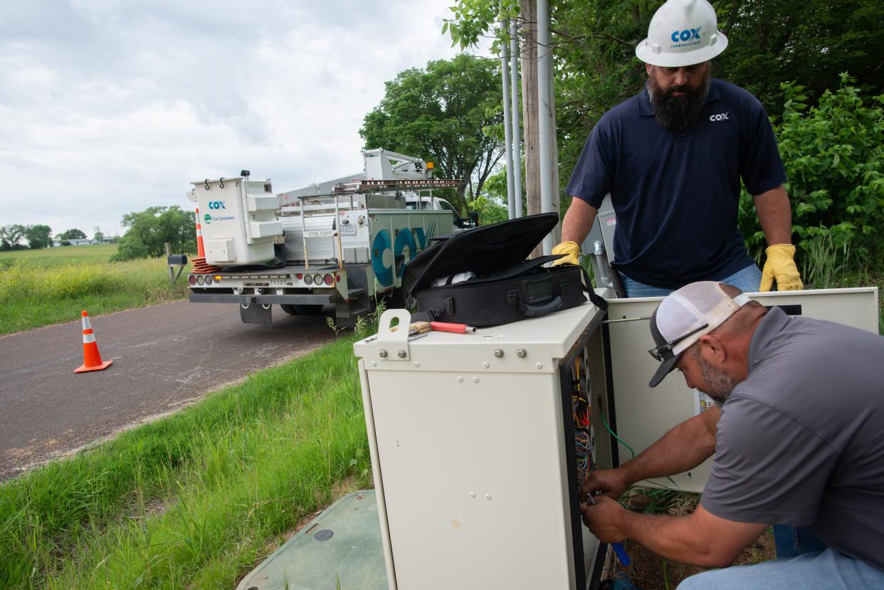 Cox Communication field technicians Lance Doyal, bottom, and Adam Colgrove in 2021 test a fiber line that connects internet to rural houses in northern Shawnee County. Kansas is getting $452 million in federal funds to use on broadband projects, and fiber connections to homes will be a top priority.