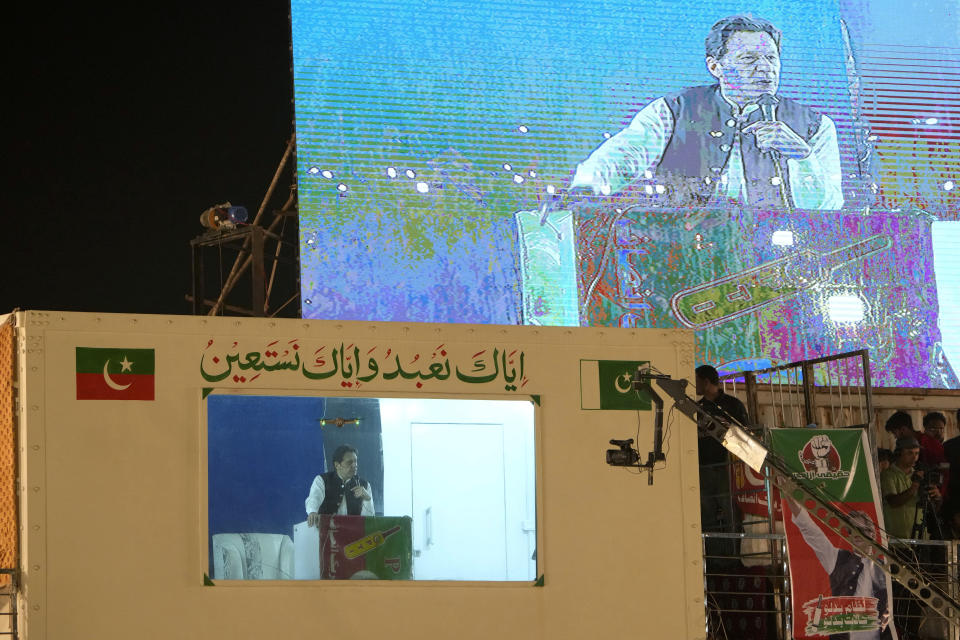 Protected by a bulletproof barrier, former Prime Minister Imran Khan speaks during a rally in Lahore, Pakistan, Sunday, March 26, 2023, to pressure the government of Shahbaz Sharif to agree to hold snap elections. (AP Photo/K.M. Chaudary)