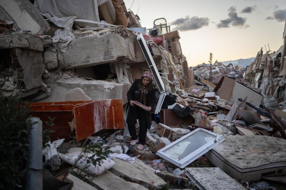 A woman collects items from a destroyed home in Antakya, Turkey.