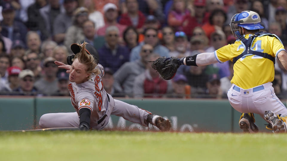 Baltimore Orioles' Kyle Stowers, left, slides safe at home as Boston Red Sox's Connor Wong, right, is unable to tag him in the third inning of a baseball game, Thursday, Sept. 29, 2022, in Boston. (AP Photo/Steven Senne)