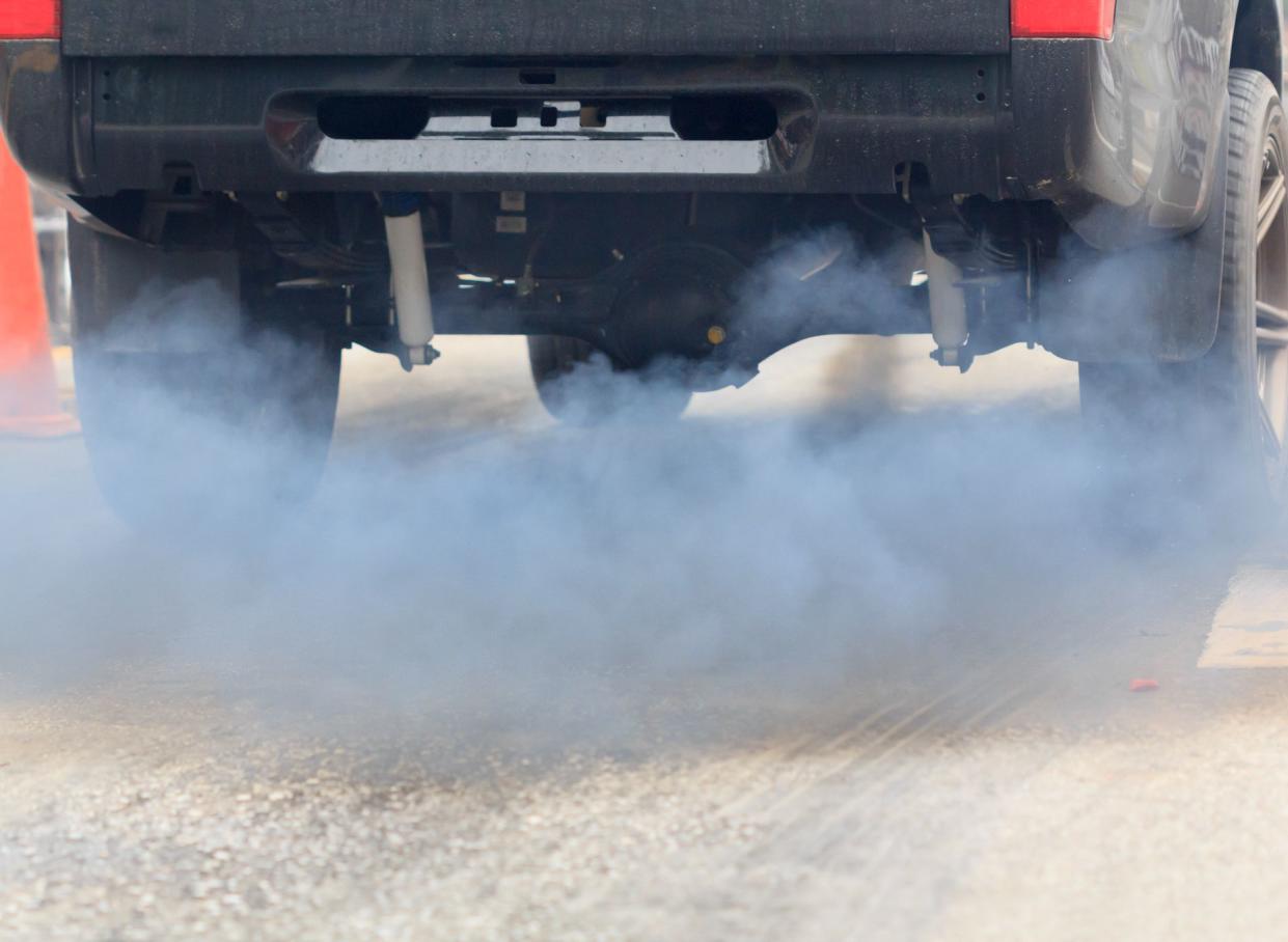 Air pollution from vehicle exhaust pipe on road