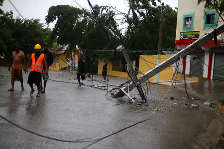 Locals walk past a fallen power pole as Hurricane Irma moves off the northern coast of the Dominican Republic, in Puerto Plata, Dominican Republic September 7, 2017. REUTERS/Ivan Alvarado