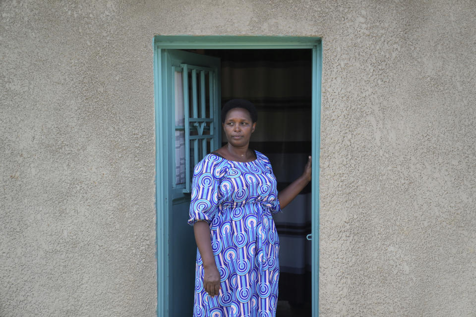 Jeanette Nyirabashyitsi, 45, stands in the doorway of her home at the Mybo reconciliation village in Nyamata, Rwanda, Friday, April 5, 2024. More than half the residents of this reconciliation village are women, and their projects — which include a basket-weaving cooperative as well as a money saving program — have united so many of them that it can seem offensive to inquire into who is Hutu and who is Tutsi. (AP Photo/Brian Inganga)