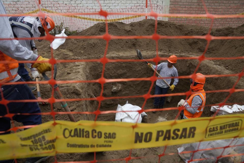 Gas workers dig where bones and vessels were discovered by workers laying a natural gas line for the Calidda gas company in the Carabayllo district on the outskirts of Lima, Peru, Friday, Sept. 22, 2023. Eight burial offerings from the pre-Inca Ychsma culture have been identified by archeologists so far, according to lead archeologist Jesus Bahamonde. (AP Photo/Martin Mejia)