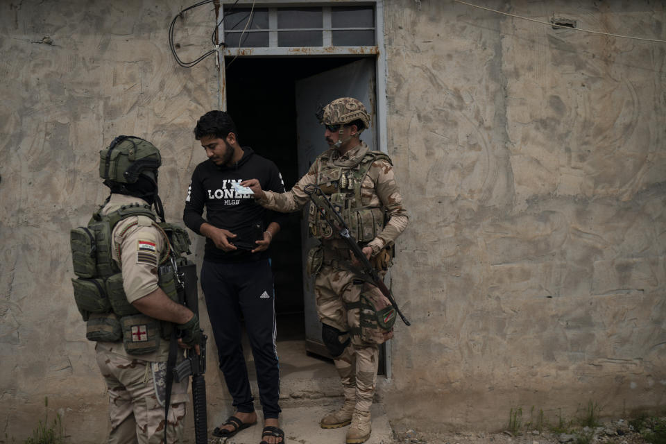 In this April 5, 2019 photo, Iraqi army 20th division soldiers check the ID of a man during a raid in Badoush, Iraq. A year and a half after the Islamic State group was declared defeated in Iraq, efforts to find remnants rely on intelligence operations, raids and searches for sleeper cells among the population. (AP Photo/Felipe Dana)