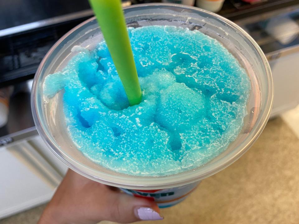 a hand holding a large 7/11 cup of blue raspberry slurpee