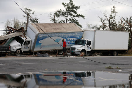 A man walks past trucks damaged by Hurricane Michael in Panama City, Florida, U.S. October 11, 2018. REUTERS/Jonathan Bachman