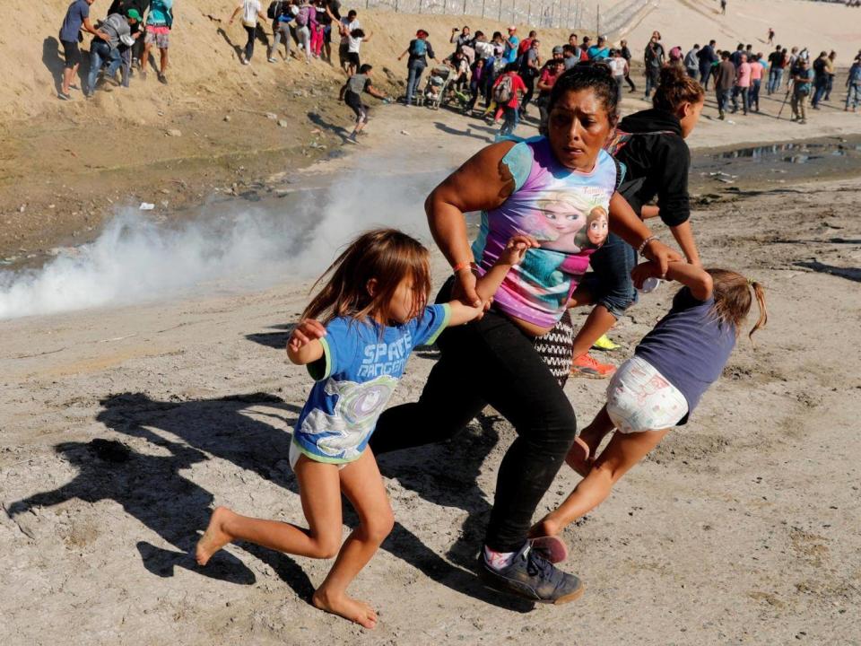 A migrant family from Honduras runs from tear gas fired by US border patrol at Mexico border (Reuters)