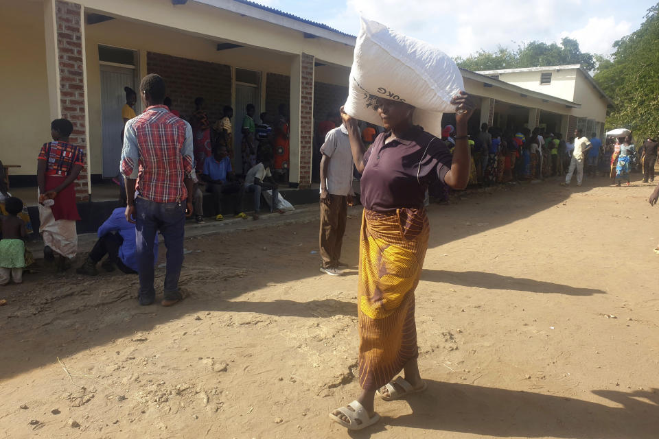 A woman carries a bag of maize meal received at a United Nations World Food Programme distribution center in Neno district, southern Malawi, Sunday, March 24, 2024. A new drought has left millions facing hunger in southern Africa as they experience the effects of extreme weather that scientists say is becoming more frequent and more damaging. (AP Photo/Kenneth Jali)